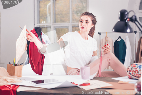 Image of Fashion designers working in studio sitting on the desk