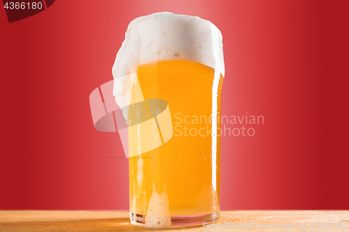 Image of glass of cold frothy lager beer on an old wooden table