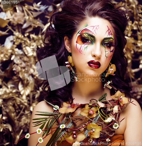 Image of beauty woman with face art and jewelry from flowers orchids clos