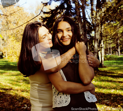 Image of mature mother with daughter outside hugging in park