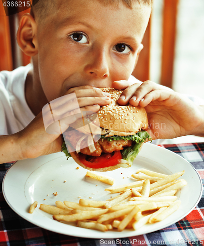 Image of little cute boy 6 years old with hamburger and french fries maki