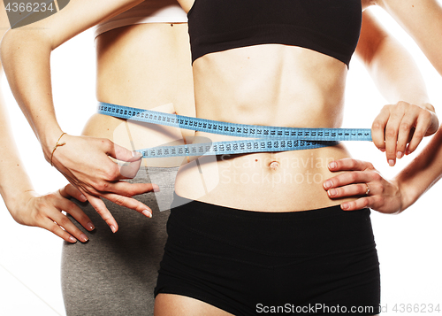 Image of two sport girls measuring themselves isolated on white