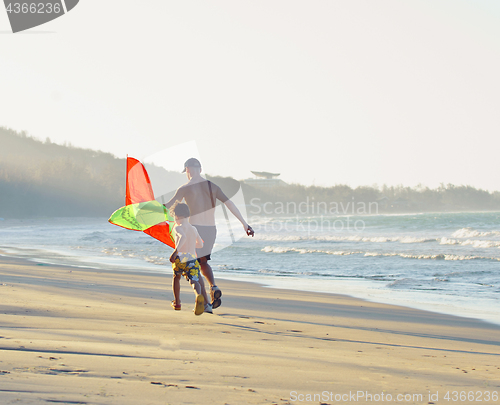 Image of father with son, sunset at the seacoast with kite, happy family 