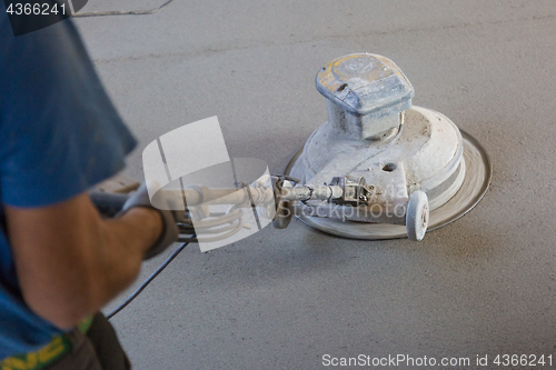 Image of Laborer polishing sand and cement screed floor.