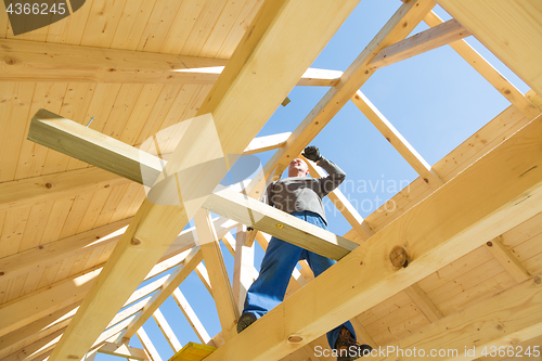 Image of Builder at work with wooden roof construction.