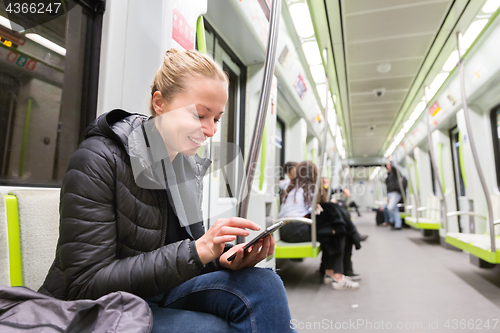 Image of Young girl reading from mobile phone screen in metro.