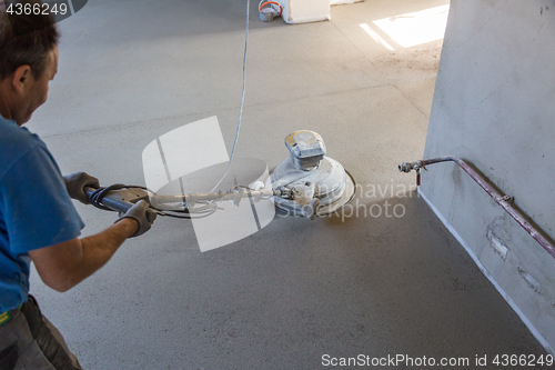 Image of Laborer polishing sand and cement screed floor.