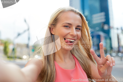 Image of happy young woman taking selfie on city street