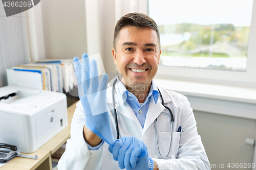 Image of smiling doctor with protective gloves at clinic