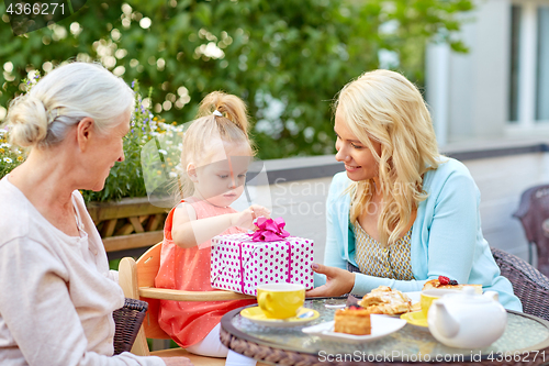 Image of happy mother giving present to daughter at cafe