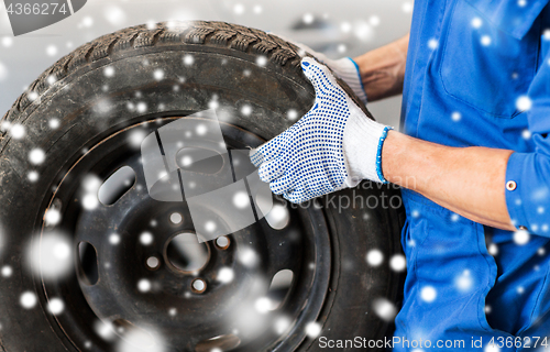 Image of close up of auto mechanic with car tire