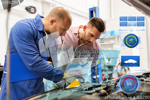 Image of auto mechanic with clipboard and man at car shop