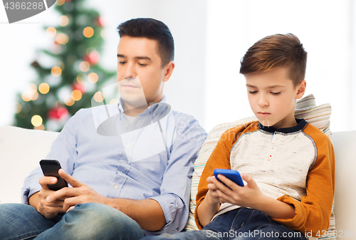 Image of father and son with smartphones at christmas