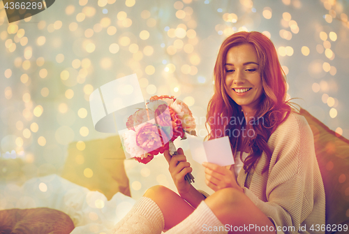 Image of happy woman with flowers and greeting card at home