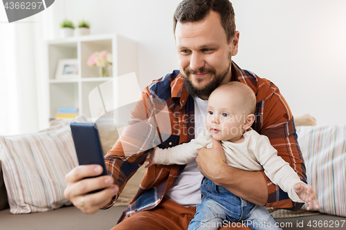 Image of happy father with baby boy taking selfie at home