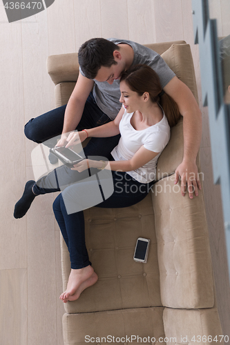 Image of couple relaxing at  home with tablet computers