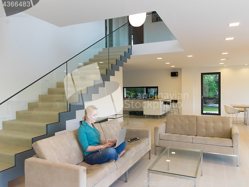 Image of Young woman using laptop at home