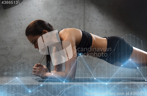 Image of woman doing plank exercise on mat in gym