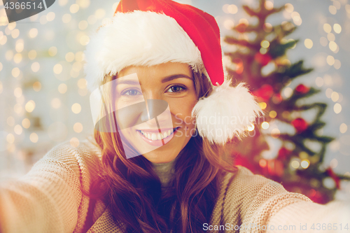 Image of happy woman taking selfie over christmas tree