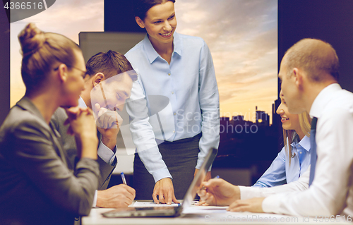 Image of smiling female boss talking to business team