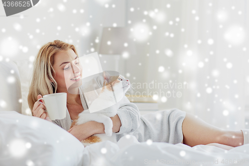 Image of happy woman with coffee and cat in bed at home
