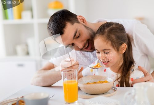 Image of happy family eating flakes for breakfast at home