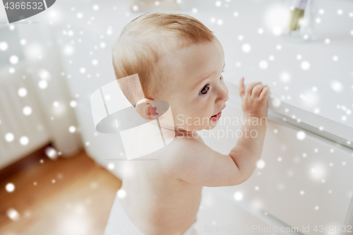 Image of happy little baby boy or girl holding to table