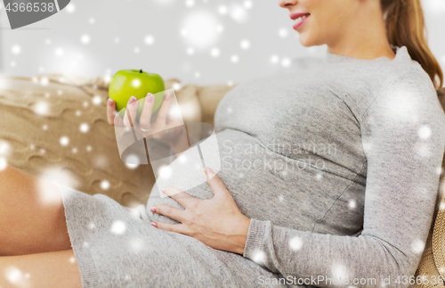 Image of happy pregnant woman with green apple