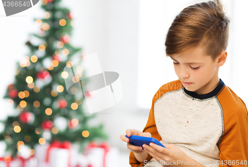 Image of close up of boy with smartphone at christmas