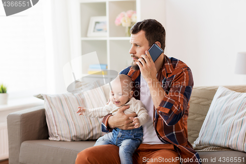 Image of father with baby calling on smartphone at home