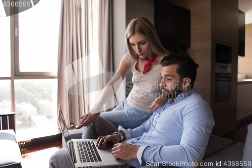 Image of couple relaxing at  home using laptop computers