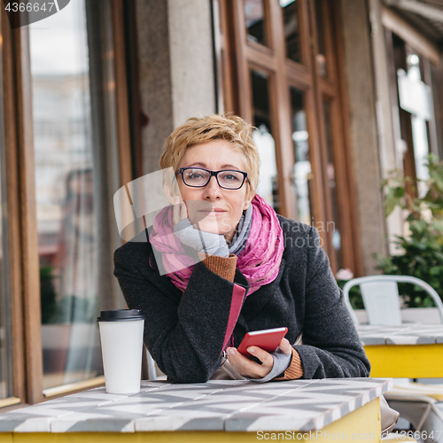 Image of Dreamy woman with phone in cafe