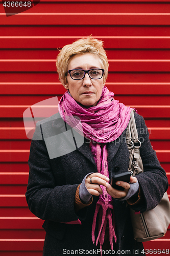 Image of Woman with phone at red fence