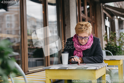 Image of Woman surfing phone in cafe