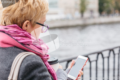 Image of Woman using smartphone at river
