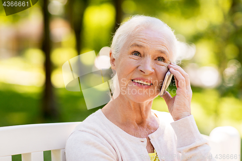 Image of happy senior woman calling on smartphone in summer