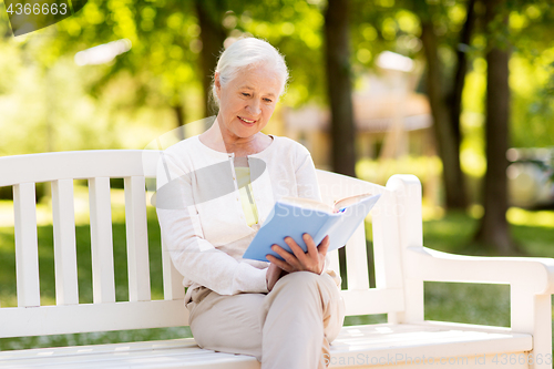 Image of happy senior woman reading book at summer park