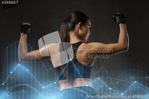 Image of young woman flexing muscles in gym