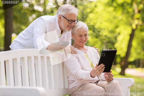 Image of happy senior couple with tablet pc at summer park