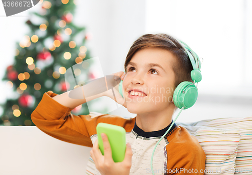 Image of boy with smartphone and headphones at christmas