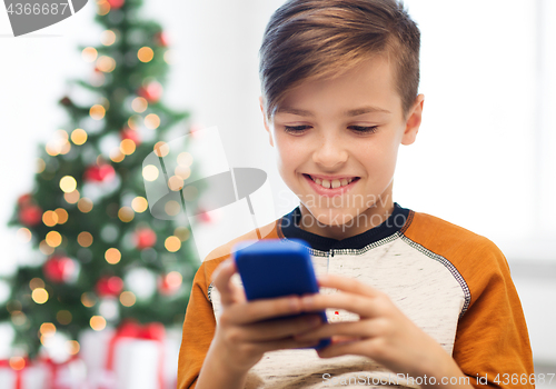 Image of close up of happy boy with smartphone at christmas