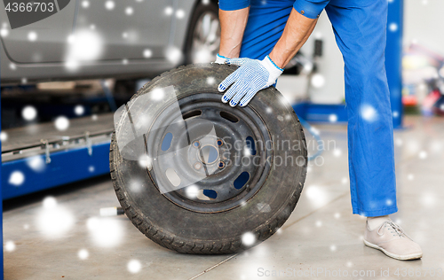 Image of auto mechanic changing car tire at workshop