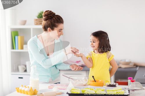 Image of happy mother and daughter baking at home