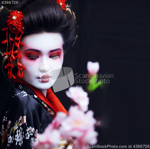 Image of young pretty geisha in kimono with sakura and decoration
