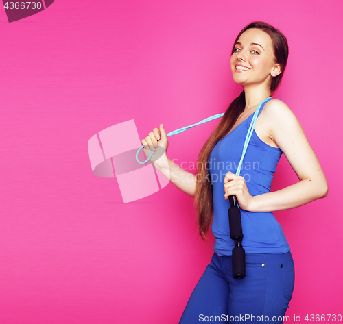 Image of young happy slim girl with skipping rope on pink background