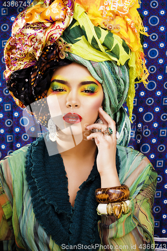 Image of beauty bright woman with creative make up, many shawls on head like cubian, ethno look closeup