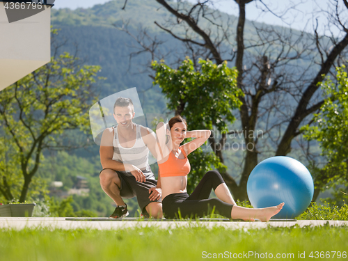 Image of woman with personal trainer doing morning yoga exercises