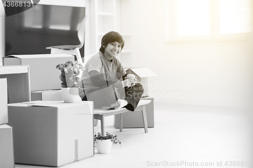 Image of boy sitting on the table with cardboard boxes around him