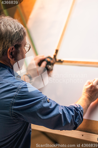 Image of The mature creative engineer working with project on drawing board