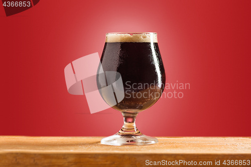 Image of glass of cold frothy dark beer on an old wooden table